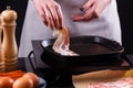 Young woman in a gray apron fries bacon Royalty Free Stock Photo