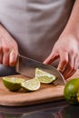 Young woman in a gray aprons cut lime Royalty Free Stock Photo