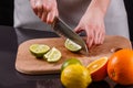 Young woman in a gray aprons cut lime Royalty Free Stock Photo