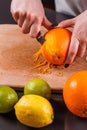 Young woman in a gray aprons, cuts an orange zest Royalty Free Stock Photo