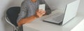 Woman in gray dress a sitting at the table and using smartphone banner