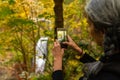 A young woman with gray hair takes photographs of the Multnomah waterfall in the Columbia River Gorge, Oregon