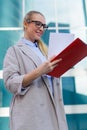 The young business woman holds in her hands folder with documents and cup of coffee. Businesswoman standing next to the business Royalty Free Stock Photo