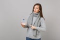 Young woman in gray sweater, scarf pointing index finger on daily pill box isolated on grey wall background. Healthy