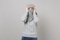 Young woman in gray sweater wrapping covering face with scarf put hands on head on grey background. Healthy