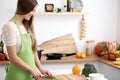 Young woman in the green apron cooking in the kitchen. Housewife slicing fresh salad Royalty Free Stock Photo