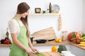Young woman in the green apron cooking in the kitchen. Housewife slicing fresh salad. Royalty Free Stock Photo