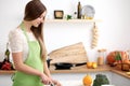 Young woman in the green apron cooking in the kitchen. Housewife slicing fresh salad. Royalty Free Stock Photo