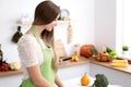 Young woman in the green apron cooking in the kitchen. Housewife slicing fresh salad. Royalty Free Stock Photo