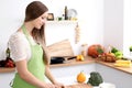 Young woman in the green apron cooking in the kitchen. Housewife slicing fresh salad Royalty Free Stock Photo