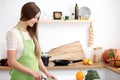 Young woman in the green apron cooking in the kitchen. Housewife slicing fresh salad Royalty Free Stock Photo