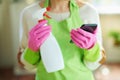 Woman with cleaning agent reading about product using phone Royalty Free Stock Photo