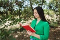 Young woman with a green blouse, enjoying reading a book in the shade of trees. Royalty Free Stock Photo