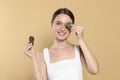 Young woman with green tea bags on beige background. Eye skin care Royalty Free Stock Photo