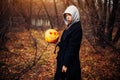 Young woman in a grey hood holding the halloween pumpkin