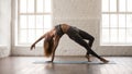 Young woman practicing yoga, standing in Wild Thing pose, Camatkarasana