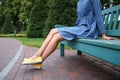 Young woman in gumshoes resting on bench outdoors