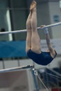 Young woman gymnast hanging on uneven bars at the championship