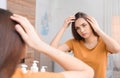 Young woman with hair loss problem looking in mirror Royalty Free Stock Photo