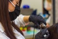 Young woman with hair rollers, young woman in the hairdresser salon, the hairdresser with black protective mask decorates the clie Royalty Free Stock Photo