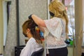 Young woman with hair rollers, young woman in the hairdresser salon, the hairdresser with black protective mask decorates the clie Royalty Free Stock Photo