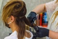 Young woman with hair rollers, young woman in the hairdresser salon, the hairdresser with black protective mask decorates the clie Royalty Free Stock Photo