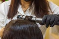 Young woman with hair rollers, young woman in the hairdresser salon, the hairdresser with black protective mask decorates the clie Royalty Free Stock Photo