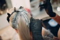 Young woman hairdresser dying hair at beauty salon. Professional hair roots coloring Royalty Free Stock Photo