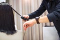 Young woman and hairdresser with hair iron making hairdo