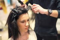 Young woman and hairdresser with hair iron making hairdo