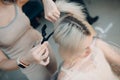 Young woman hairdresser with pin dying hair at beauty salon. Professional hair roots coloring Royalty Free Stock Photo