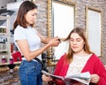 Young woman hairdresser working with female's hair in hairdressing salon Royalty Free Stock Photo