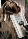 Young woman in a hairdressing salon dyes her hair blond