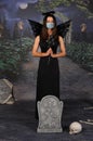 Young woman in halloween black angel costume wearing protective medical face mask against coronavirus Covid-19. New Royalty Free Stock Photo