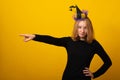 Young woman in a Halloween evil witch costume. Funny young girl wearing witch costume for Halloween party on yellow background