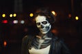 Young woman with Halloween face art. Street portrait. Night city background. Close up