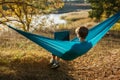 Young woman in hammok using laptop working outdoor facing lake on a sunset Royalty Free Stock Photo