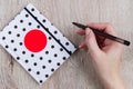 Young woman hand hold black pen and polka dot cover notebook on  wooden table Royalty Free Stock Photo