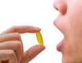 Young woman hand hold fish oil capsule near open mouth. Woman taking omega-3 pills. Royalty Free Stock Photo