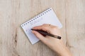 Young woman hand hold opened notebook pages with black pen on  wooden table. To do list handwriting Royalty Free Stock Photo