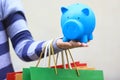 Young woman hand holding blue piggy bank and colorful shopping bags on white background, saving money for shopping concept Royalty Free Stock Photo