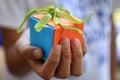 Young woman hand holding a colorful  small gift box with a green cananga odorata flower on it. Royalty Free Stock Photo