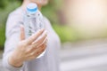 young woman hand holding give fresh drinking water bottle from a plastic in the park