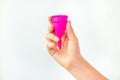 Young woman hand holding a pink menstrual cup