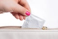 Young woman hand pulling a condom from a leather bag, white background