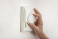 Young woman hand switch on temperature regulator on wall panel