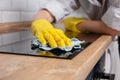 Young woman hands cleaning a modern black induction hob by a rag, housework