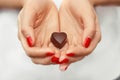 Young woman hands with dark chocolate in a shape of a heart. Enjoy healthy lifestyle. Chocolate candy. Happy days at home.