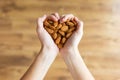 Young woman hands forming heart shape holding almonds nuts at home