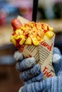 Young woman hands holding Belgian fried potatos with sausage, ketchup and sause